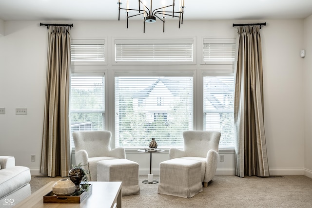 living area featuring baseboards, carpet flooring, and a notable chandelier