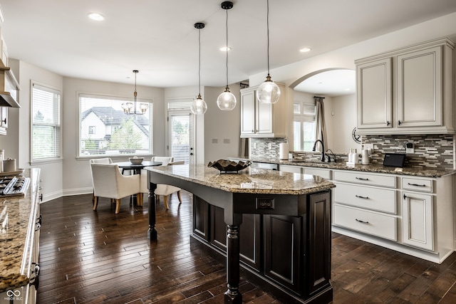 kitchen with plenty of natural light, arched walkways, and tasteful backsplash