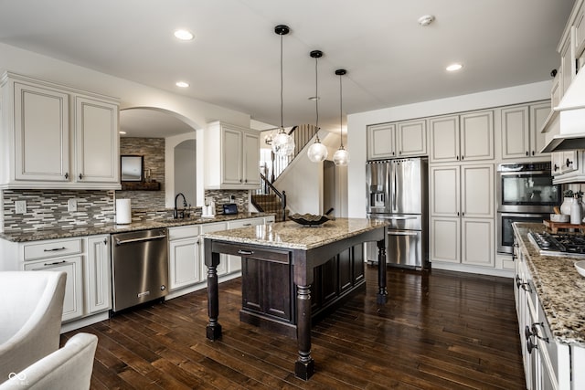 kitchen with stainless steel appliances, arched walkways, a breakfast bar, and decorative backsplash