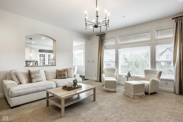 living area with arched walkways, baseboards, a notable chandelier, and a wealth of natural light