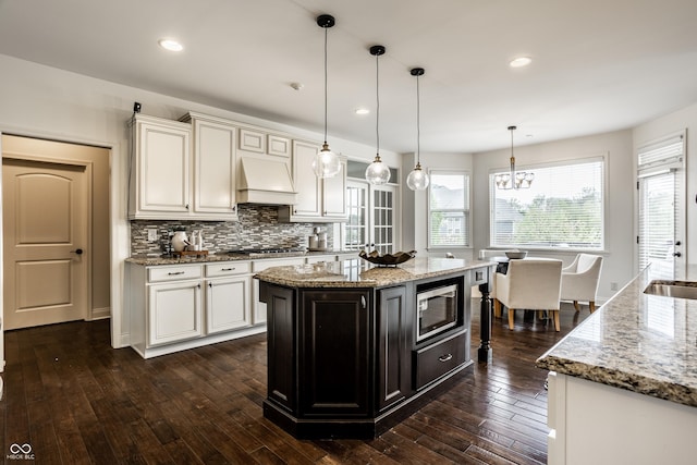 kitchen featuring custom range hood, dark wood-type flooring, light stone countertops, and stainless steel appliances