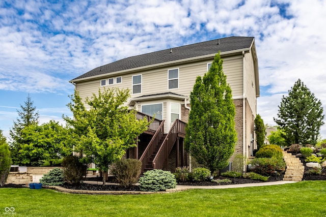 view of front facade with brick siding, a deck, stairs, and a front lawn