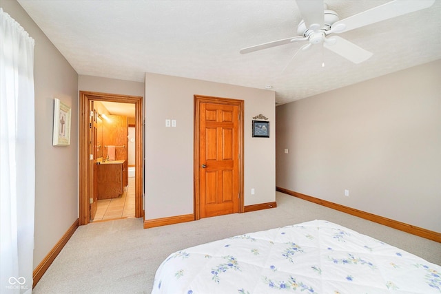 bedroom with ensuite bath, ceiling fan, baseboards, and light colored carpet