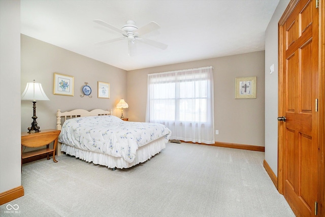 bedroom with light carpet, ceiling fan, and baseboards