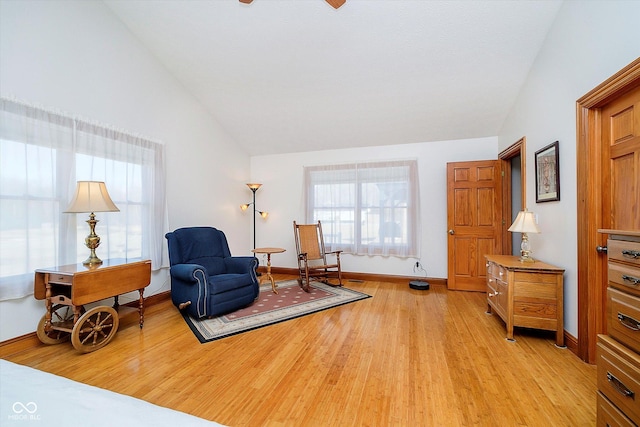 living area featuring high vaulted ceiling, light wood-style flooring, and baseboards