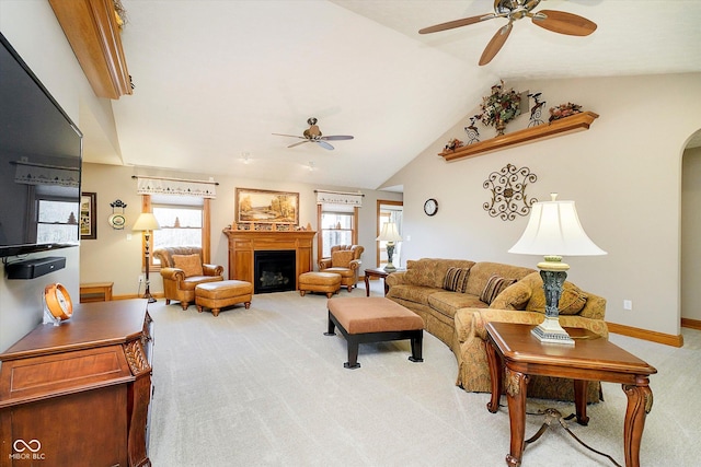 living room featuring arched walkways, a fireplace, lofted ceiling, light carpet, and ceiling fan