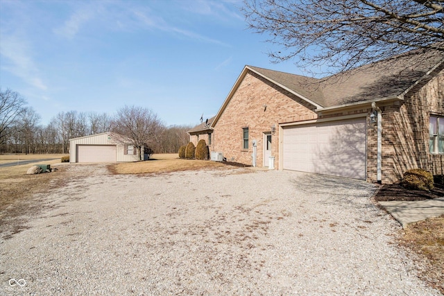 view of home's exterior featuring driveway, an outbuilding, and brick siding