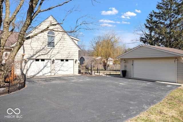 view of side of property featuring a detached garage, fence, and an outdoor structure