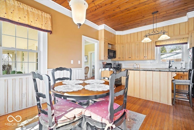 dining space featuring wainscoting, wood finished floors, wooden ceiling, and crown molding