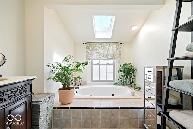 bathroom featuring a tub with jets, a skylight, and vanity