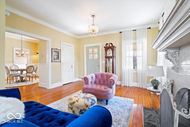 living area featuring hardwood / wood-style floors, crown molding, baseboards, and a chandelier