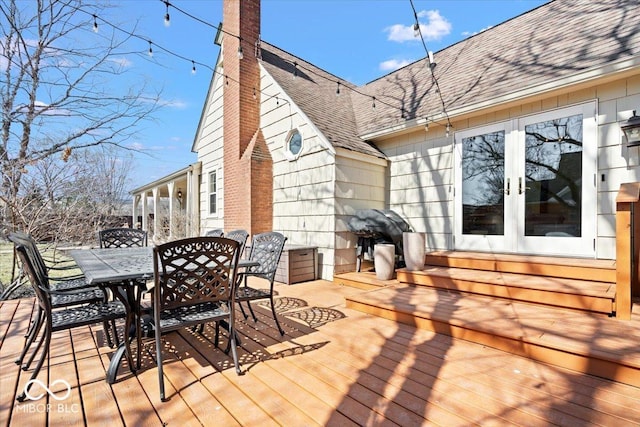 wooden terrace with outdoor dining space and french doors