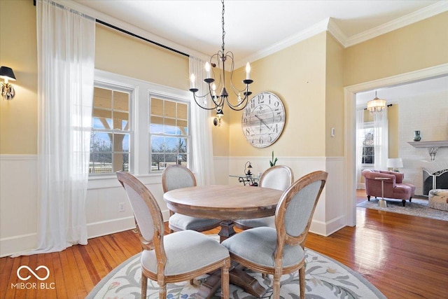 dining space featuring hardwood / wood-style floors, crown molding, a notable chandelier, and wainscoting