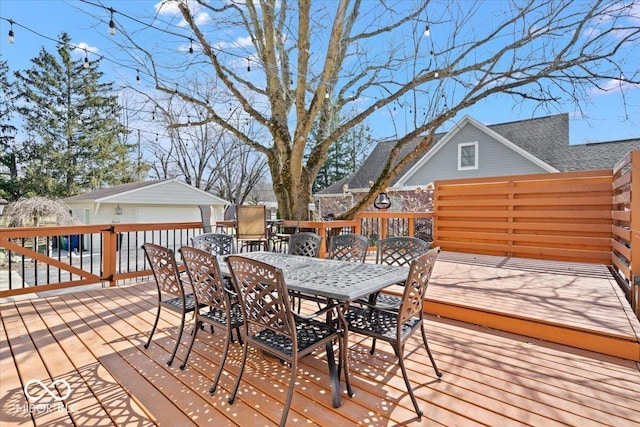 wooden terrace with outdoor dining area, an outbuilding, and a garage