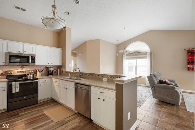 kitchen featuring tasteful backsplash, appliances with stainless steel finishes, open floor plan, a peninsula, and a sink