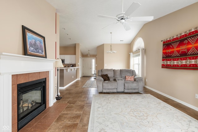 living room with ceiling fan, lofted ceiling, a tile fireplace, dark tile patterned floors, and baseboards