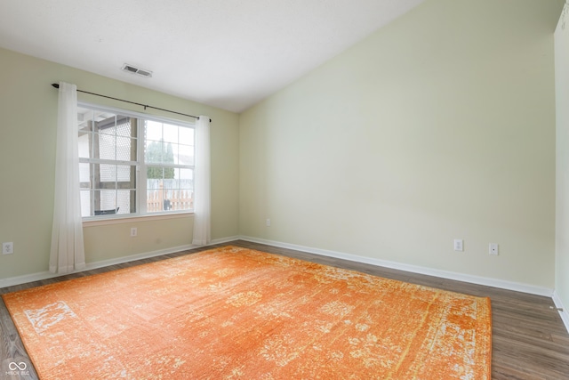 spare room with lofted ceiling, visible vents, baseboards, and wood finished floors