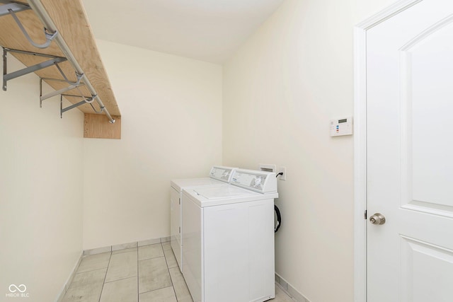 washroom featuring laundry area, light tile patterned floors, baseboards, and washer and clothes dryer