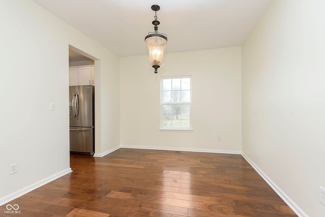 spare room featuring dark wood-style floors and baseboards