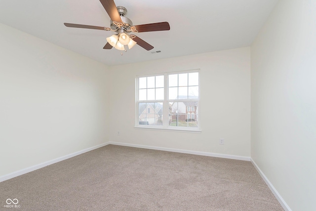 spare room with carpet flooring, visible vents, ceiling fan, and baseboards