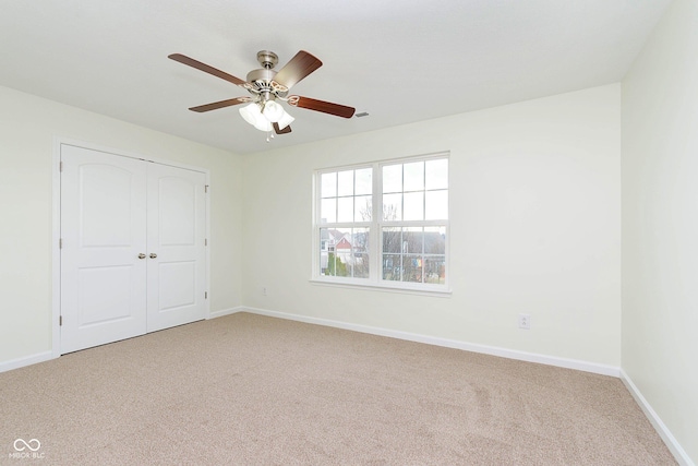 unfurnished bedroom with carpet, a closet, ceiling fan, and baseboards