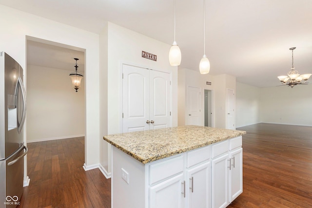 kitchen featuring stainless steel fridge, white cabinets, dark wood-style floors, light stone countertops, and a chandelier