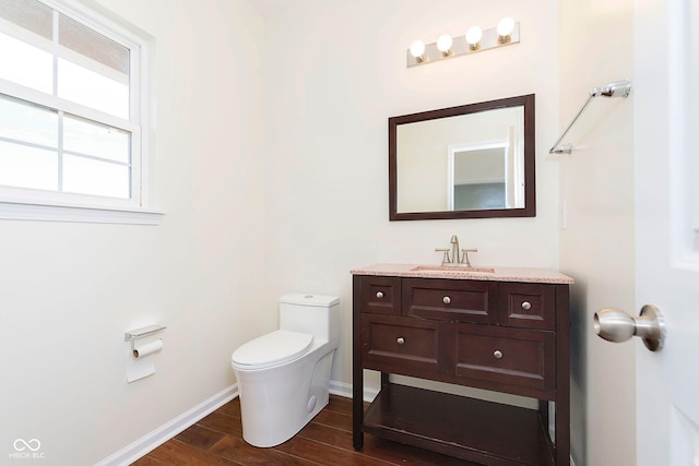 half bath featuring vanity, wood finished floors, toilet, and baseboards