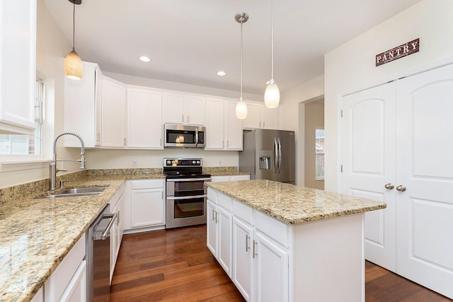 kitchen with white cabinets, appliances with stainless steel finishes, dark wood-style flooring, a center island, and a sink