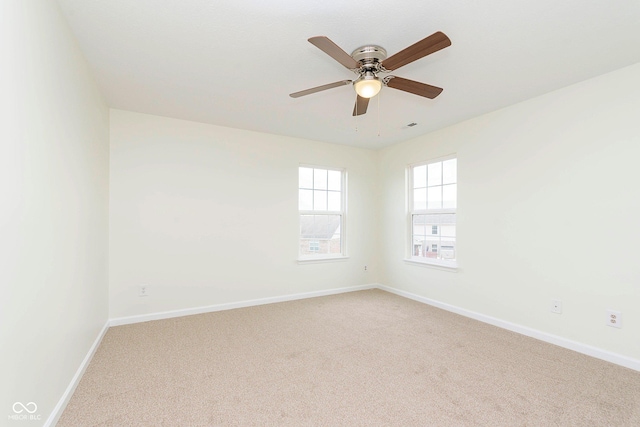 spare room featuring a ceiling fan, light colored carpet, visible vents, and baseboards