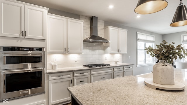 804 Whispering Oaks Dr, Carmel, IN 46032 - kitchen with wall chimney exhaust hood, appliances with stainless steel finishes, white cabinets, backsplash, and light stone countertops
