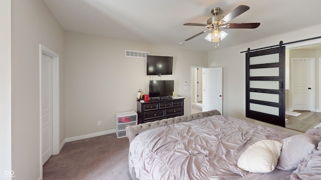 carpeted bedroom featuring visible vents, ceiling fan, baseboards, and a barn door