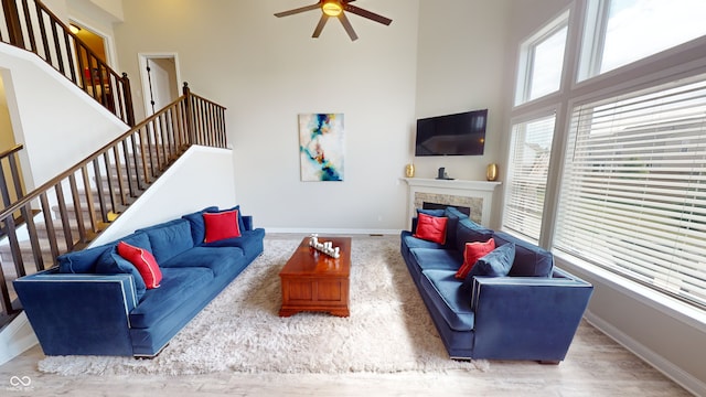 living room with stairs, a fireplace, a towering ceiling, and baseboards