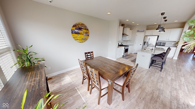 dining room with light wood finished floors, baseboards, and recessed lighting