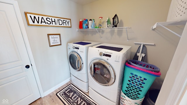 clothes washing area with laundry area, baseboards, light wood-style flooring, and washing machine and clothes dryer