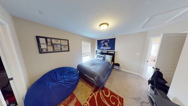 bedroom featuring attic access, a textured ceiling, baseboards, and carpet flooring