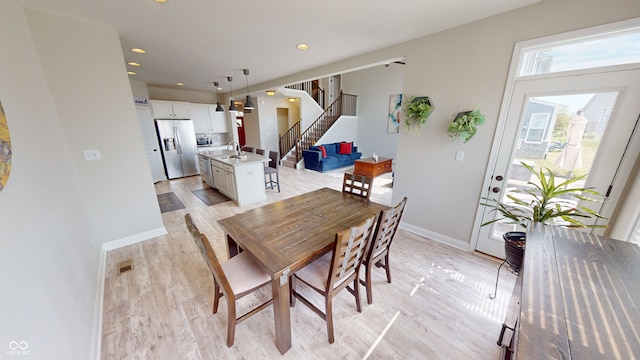 dining room with light wood-style floors, baseboards, stairway, and recessed lighting