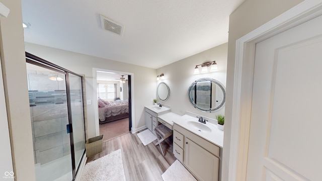 ensuite bathroom with visible vents, ensuite bathroom, a shower stall, vanity, and wood finished floors