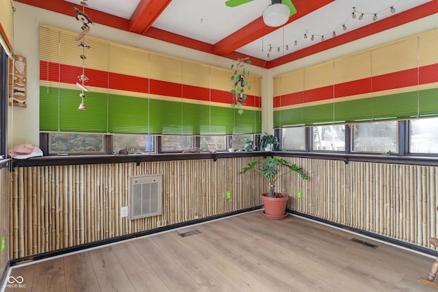 unfurnished sunroom featuring ceiling fan, beamed ceiling, and visible vents