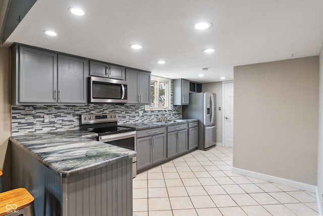 kitchen with dark countertops, appliances with stainless steel finishes, backsplash, and gray cabinetry