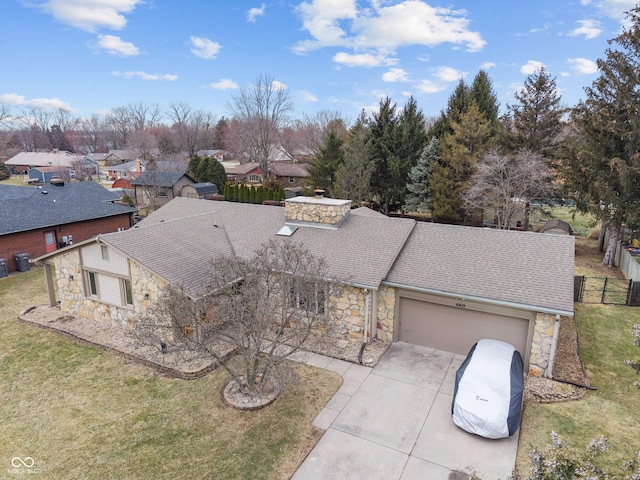 view of front facade with stone siding, concrete driveway, roof with shingles, and a front yard