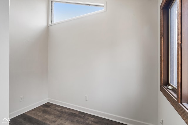 unfurnished room featuring baseboards and dark wood-type flooring