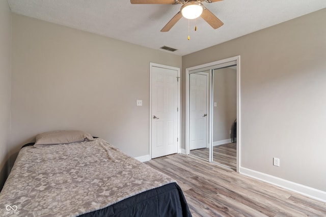 bedroom with a closet, visible vents, light wood-style flooring, ceiling fan, and baseboards