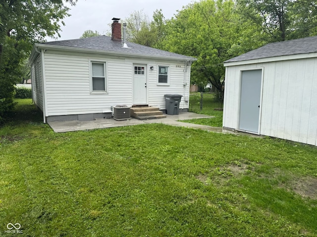 1323 S Ewing St, Indianapolis, IN 46203 - rear view of property featuring a chimney, a yard, central AC, and a shingled roof