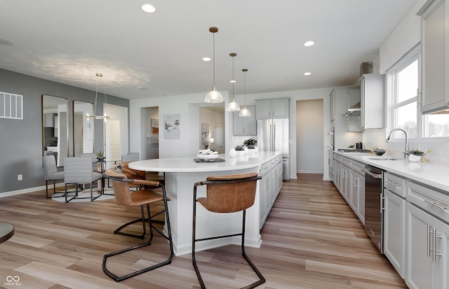 kitchen with visible vents, a kitchen island, a breakfast bar area, stainless steel appliances, and a sink