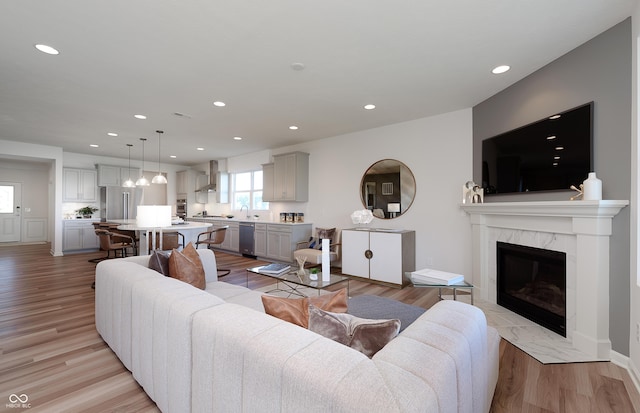 living area featuring a high end fireplace, light wood-type flooring, and recessed lighting