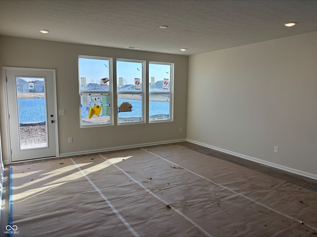 empty room with recessed lighting, a textured ceiling, and baseboards