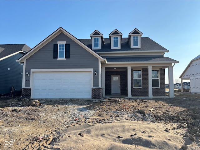 view of front of house with an attached garage, a porch, and brick siding