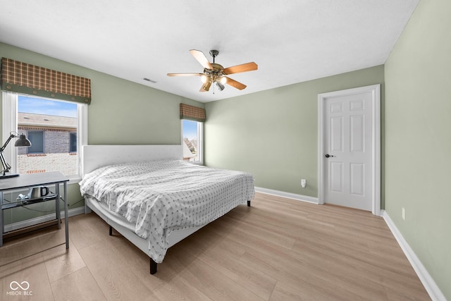 bedroom featuring light wood finished floors, a ceiling fan, visible vents, and baseboards