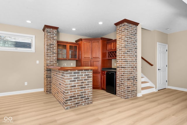 bar with wet bar, baseboards, light wood finished floors, and stairs