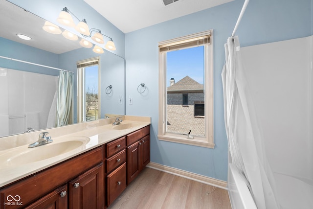 bathroom with double vanity, a sink, baseboards, and wood finished floors